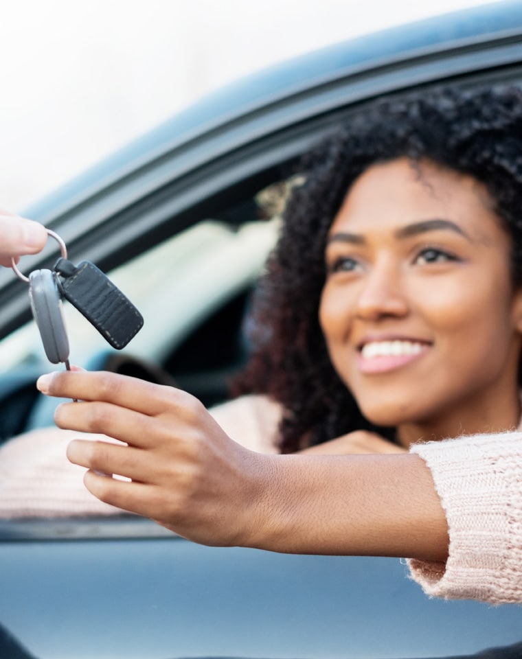 Women being handed keys after purchasing a car.
